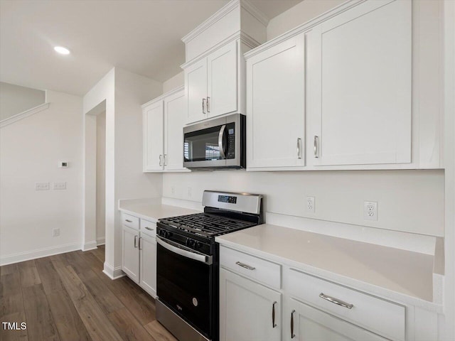 kitchen with dark wood-type flooring, baseboards, light countertops, appliances with stainless steel finishes, and white cabinetry