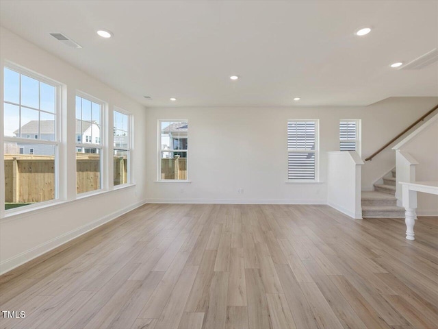 unfurnished living room with a healthy amount of sunlight, visible vents, and light wood-type flooring