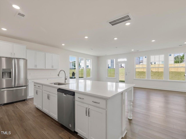 kitchen featuring dark wood-style floors, visible vents, an island with sink, a sink, and stainless steel appliances