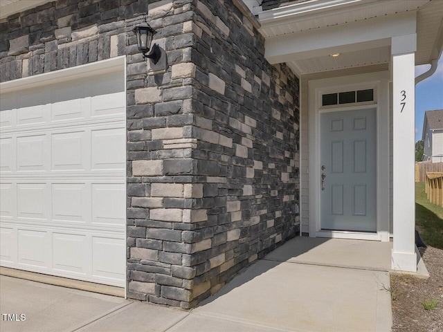 view of exterior entry featuring a garage and stone siding