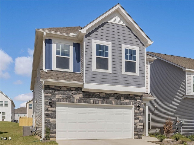 view of front of house featuring a shingled roof, central AC unit, driveway, stone siding, and an attached garage