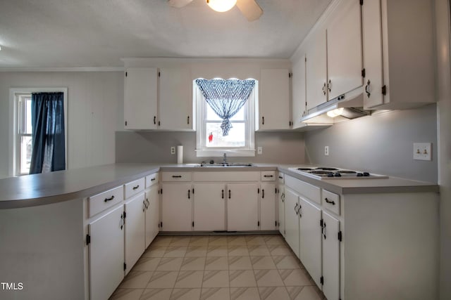 kitchen featuring under cabinet range hood, a sink, a peninsula, white cabinets, and white electric stovetop