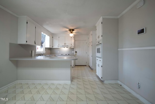 kitchen featuring a ceiling fan, white cabinetry, a peninsula, light countertops, and white oven