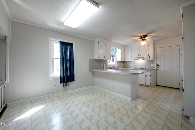 kitchen with a sink, a peninsula, white cabinets, light countertops, and ceiling fan