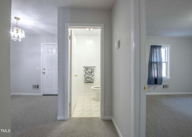 hall featuring an inviting chandelier, carpet flooring, baseboards, and visible vents