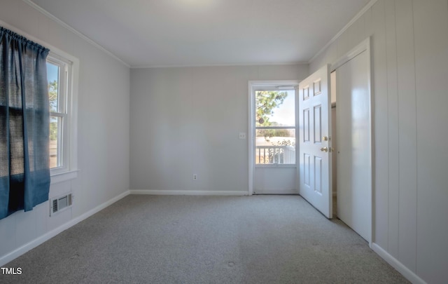 empty room with light colored carpet, a healthy amount of sunlight, visible vents, and ornamental molding