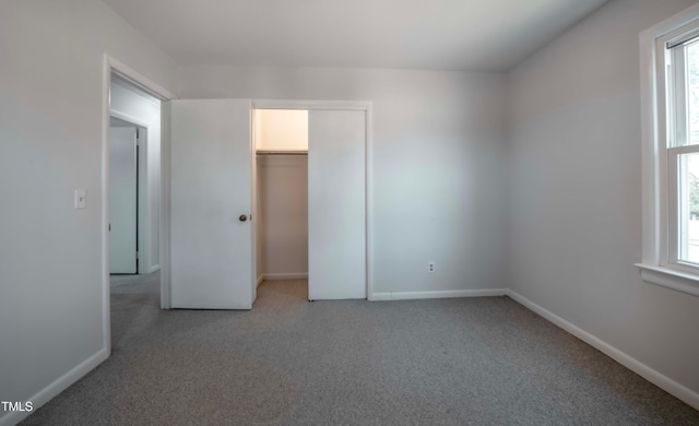 unfurnished bedroom with multiple windows, baseboards, a closet, and light carpet