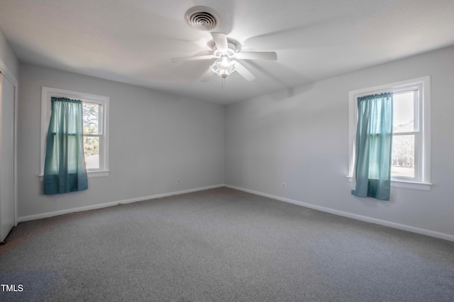 empty room with carpet, visible vents, a ceiling fan, and baseboards