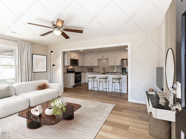 living area featuring light wood finished floors and ceiling fan