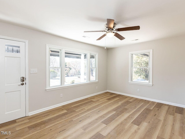 spare room featuring light wood-style flooring, visible vents, baseboards, and ceiling fan