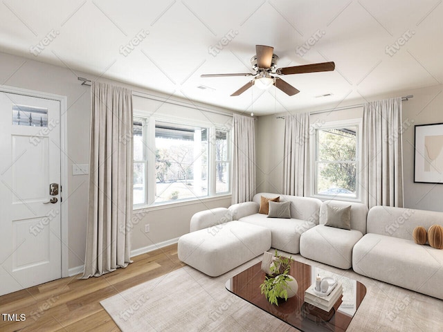 living area featuring baseboards, wood finished floors, visible vents, and ceiling fan