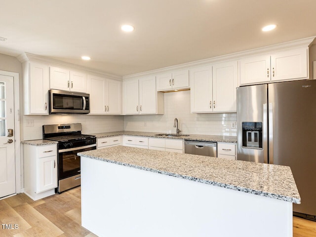 kitchen featuring light wood-style flooring, white cabinets, stainless steel appliances, and a sink