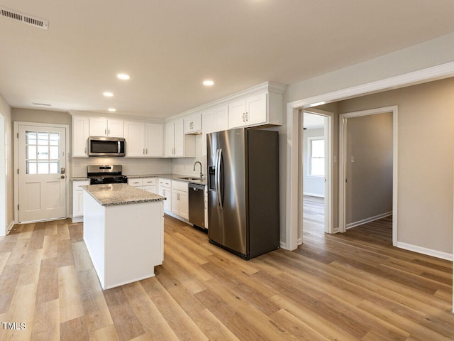 kitchen featuring stainless steel appliances, light wood finished floors, visible vents, and white cabinetry