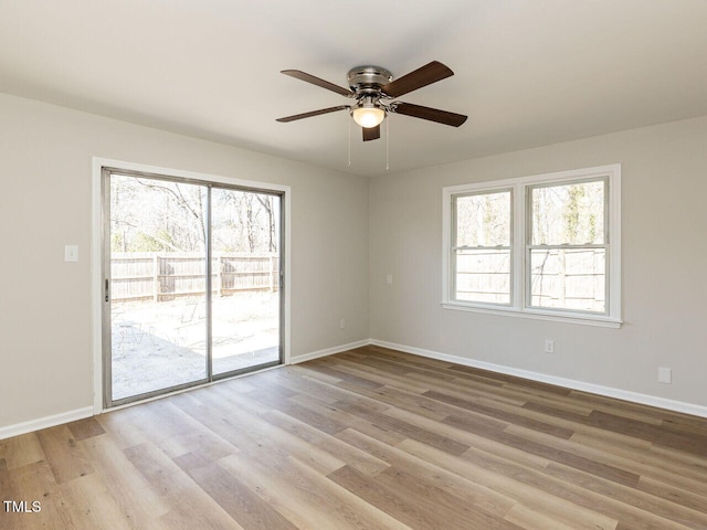 empty room featuring light wood-type flooring, baseboards, and a ceiling fan