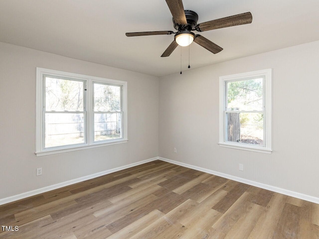 spare room with baseboards, wood finished floors, and a ceiling fan