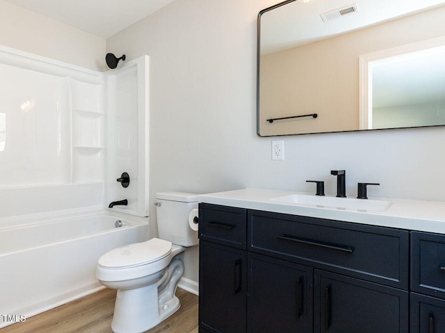 bathroom with visible vents, toilet, wood finished floors,  shower combination, and vanity