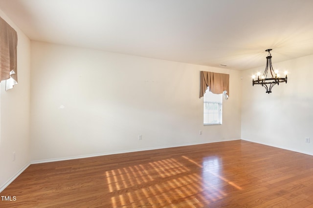 1009 Limeberry Ct, Clayton, NC 27520 - unfurnished room with wood finished floors, baseboards, and an inviting chandelier