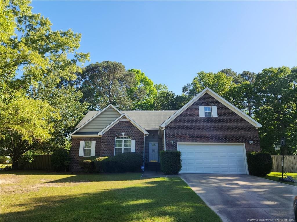 view of front facade featuring brick siding, concrete driveway, a front yard, and fence