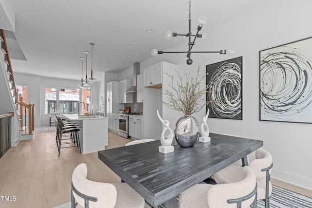 dining area featuring a notable chandelier, stairs, light wood-type flooring, and baseboards