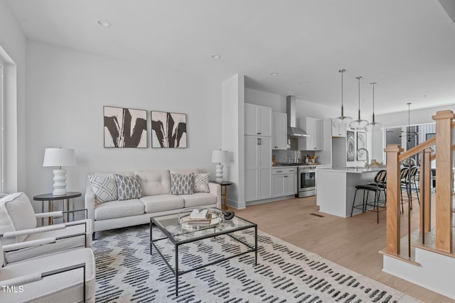 living area featuring recessed lighting, light wood-style flooring, and stairs