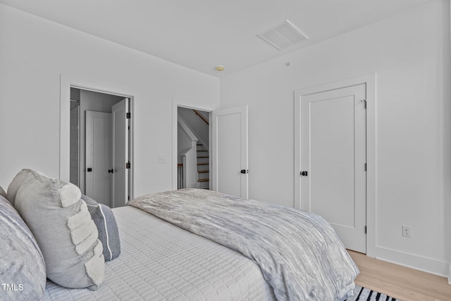 bedroom featuring light wood-style flooring, baseboards, and visible vents