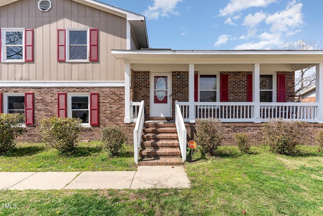 split level home with board and batten siding, a porch, brick siding, and a front yard