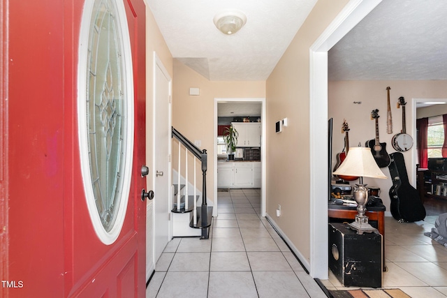 foyer with stairway, baseboards, and light tile patterned flooring