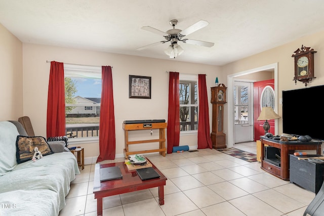 living room featuring a wealth of natural light, baseboards, ceiling fan, and light tile patterned flooring