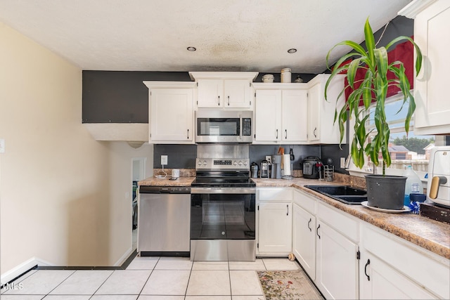 kitchen featuring white cabinetry, stainless steel appliances, light countertops, light tile patterned floors, and baseboards