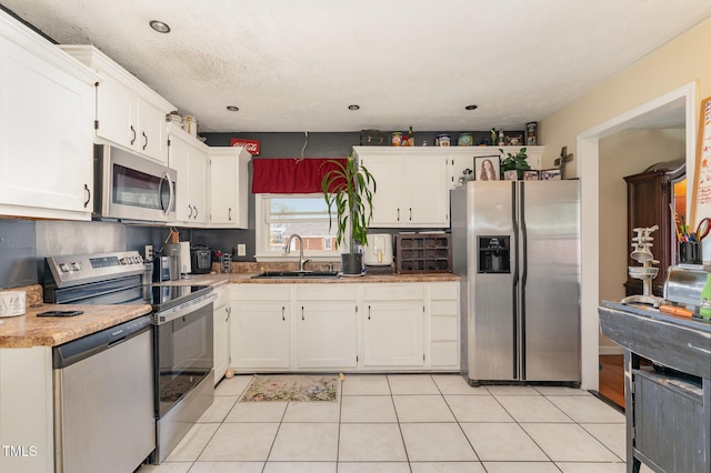 kitchen featuring a sink, stainless steel appliances, white cabinets, and light tile patterned floors