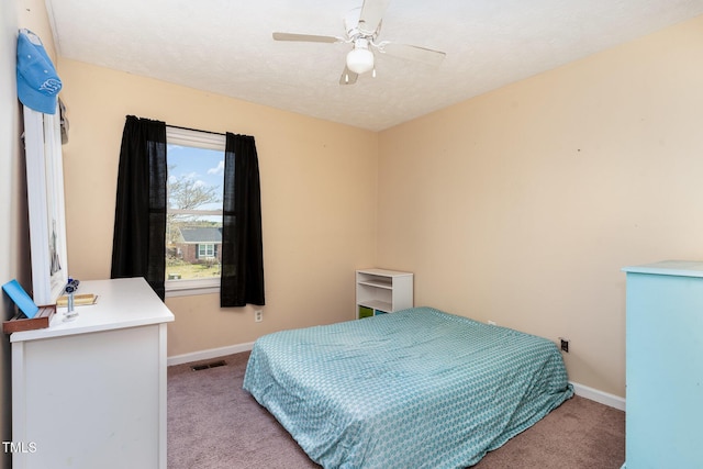 carpeted bedroom featuring visible vents, a textured ceiling, baseboards, and a ceiling fan