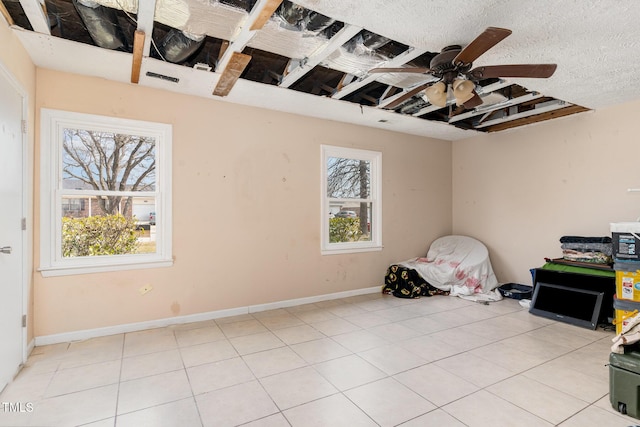 unfurnished room with light tile patterned floors, a ceiling fan, baseboards, and a textured ceiling