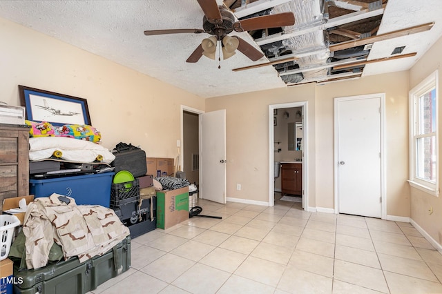 bedroom with a ceiling fan, baseboards, light tile patterned flooring, a textured ceiling, and connected bathroom