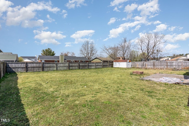 view of yard with an outbuilding, a fenced backyard, and a shed