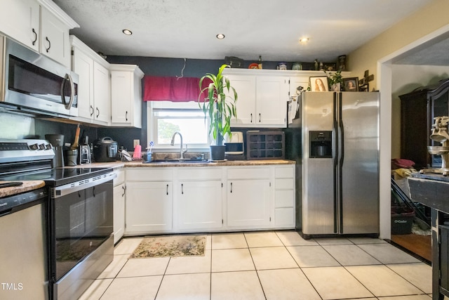 kitchen featuring white cabinets, light tile patterned floors, appliances with stainless steel finishes, and a sink