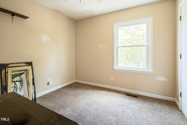 interior space featuring carpet floors, baseboards, visible vents, and ceiling fan