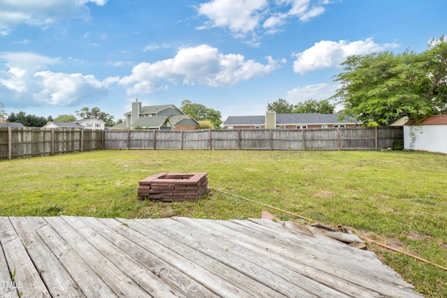 wooden terrace featuring a lawn, a fenced backyard, and a fire pit