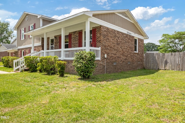 view of property exterior with fence, a lawn, a porch, and brick siding