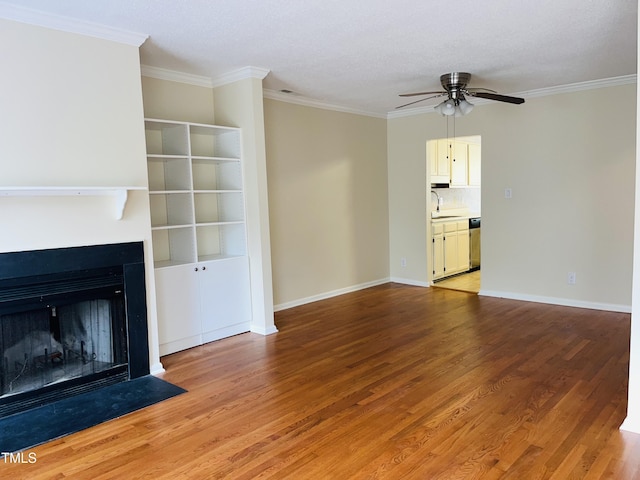 unfurnished living room with a sink, ornamental molding, light wood-type flooring, and ceiling fan