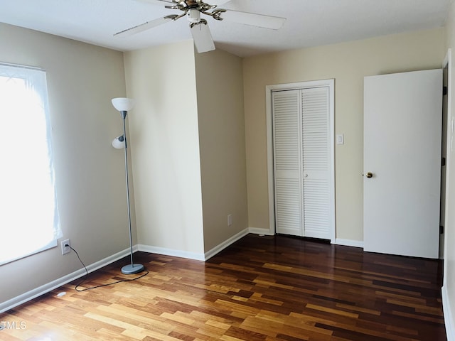 unfurnished bedroom featuring multiple windows, wood finished floors, and baseboards