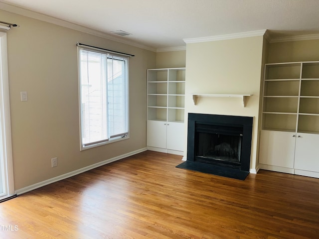 unfurnished living room featuring visible vents, wood finished floors, a fireplace, and crown molding