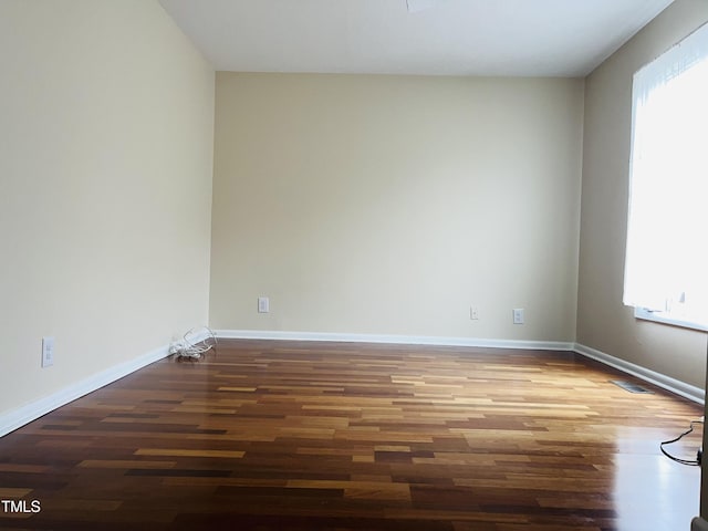 unfurnished room with visible vents, baseboards, and wood finished floors