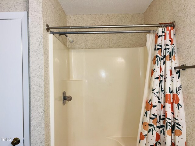 bathroom featuring curtained shower and a textured ceiling