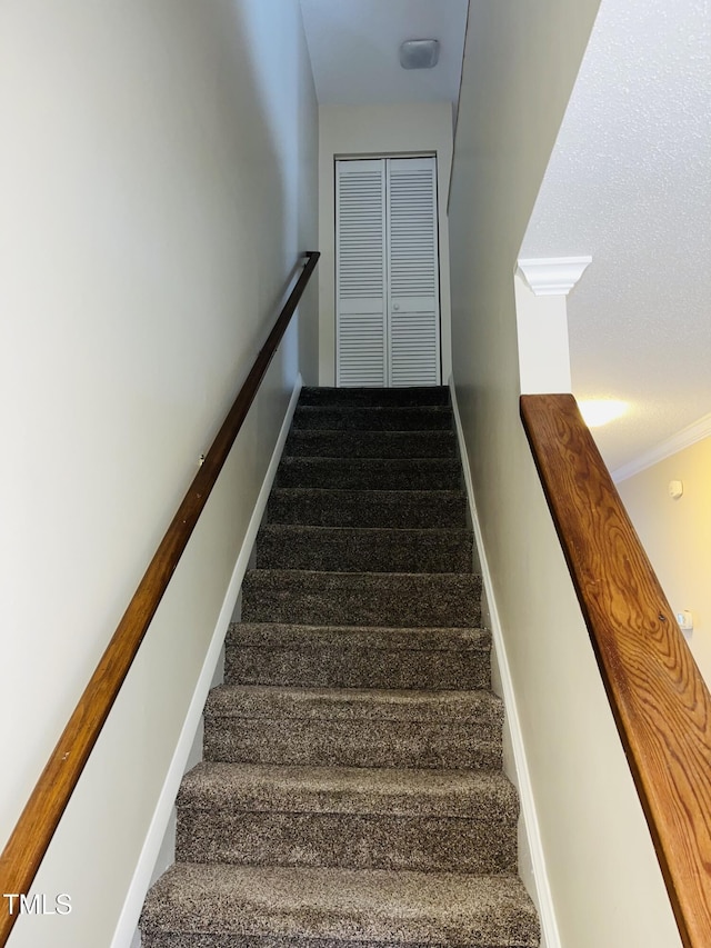 staircase with baseboards, ornamental molding, and carpet flooring