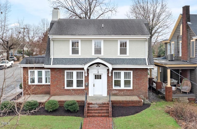 view of front of house with brick siding, roof with shingles, and a chimney