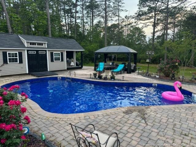 outdoor pool featuring an outdoor structure, a patio area, and an exterior structure