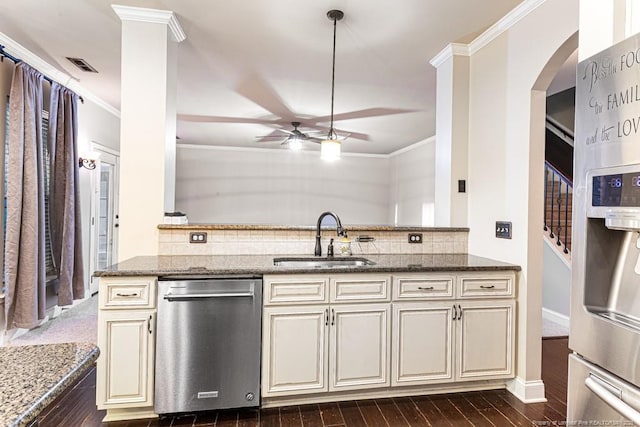 kitchen with a sink, cream cabinets, arched walkways, appliances with stainless steel finishes, and ceiling fan