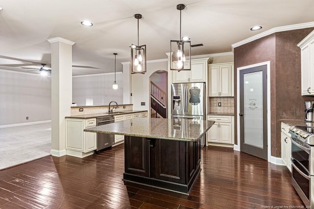 kitchen with tasteful backsplash, ornamental molding, light stone counters, appliances with stainless steel finishes, and a ceiling fan