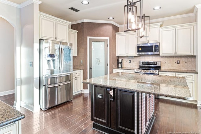 kitchen with dark wood-type flooring, tasteful backsplash, arched walkways, appliances with stainless steel finishes, and crown molding