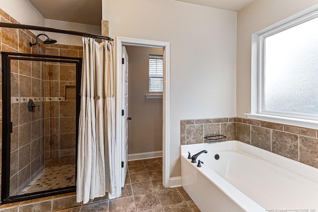 bathroom with baseboards, a garden tub, and a shower stall